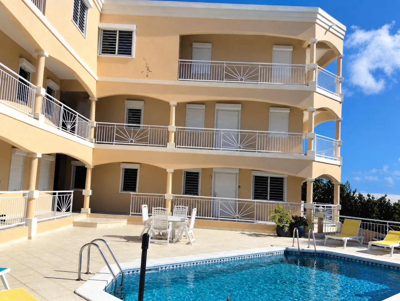 Pale yellow property with balconies overlooking a swimming pool