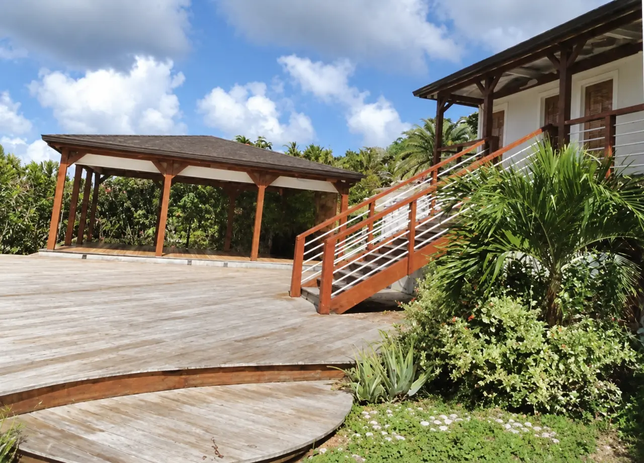 Timber decking, railings and a garden pavilion framed by tropical planting.