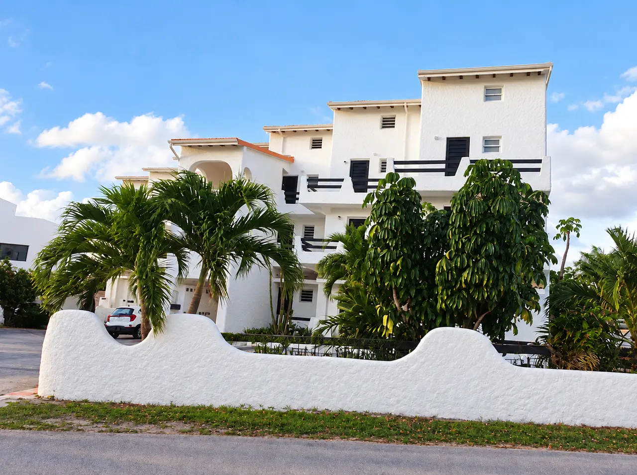 Light-coloured property with palms and a landscaped entrance